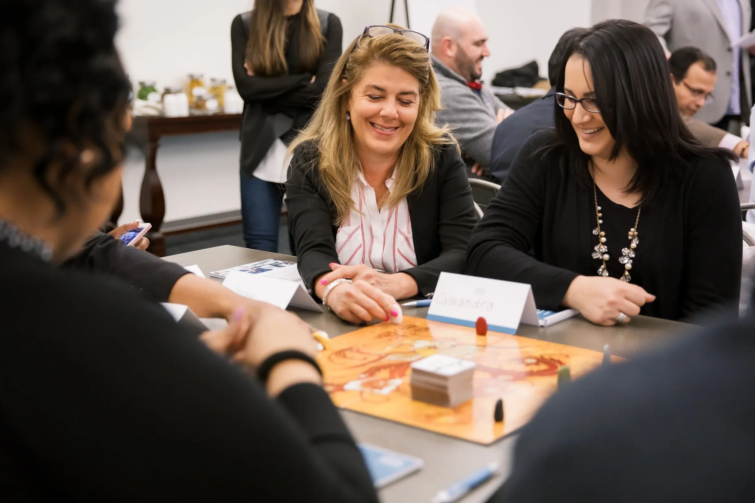 Colleagues laugh together over a tabletop activity during a workshop.