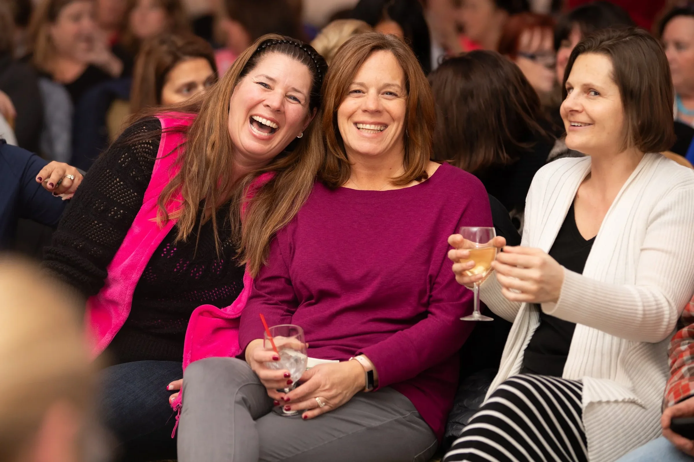 Three guests laugh together while seated at an evening event.